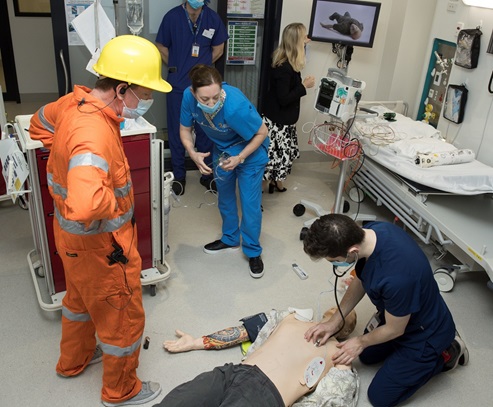 Participants taking part in a SimStart training exercise, providing medical care to a simulated manikin on the floor