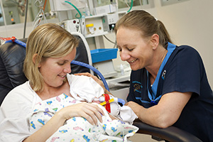 Mum holding baby with nurse in NICU