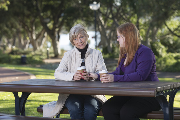 Mother and daughter talking at a bench in the park