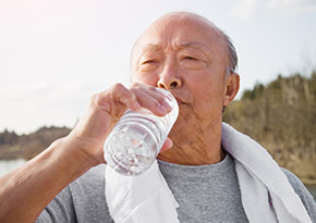 Elderly man drinking a bottle of water after a run