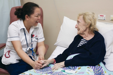 Older female patient speaking to nurse in hospital