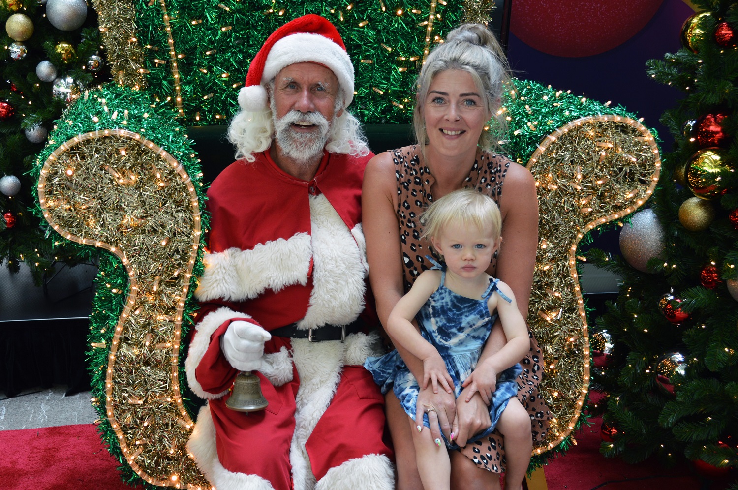 18-month old Maddi sitting on her mother's lap, next to Santa